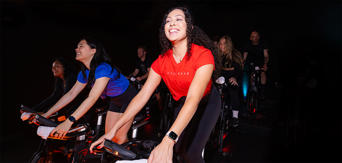 CycleBar class cycling at class with woman at forefront smiling